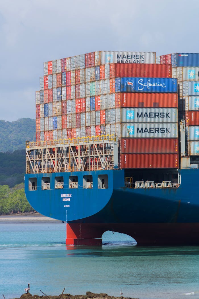 why-choose-us A cargo ship loaded with containers navigates the Panama Canal under clear skies.