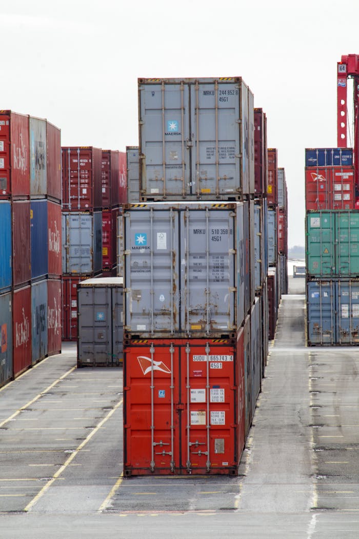 team-04 Vertical shot of colorful shipping containers stacked at an industrial port, showcasing logistics.