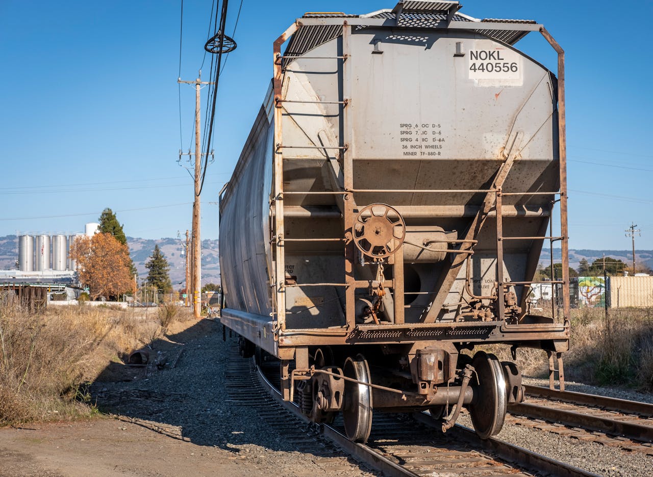 An industrial cargo train wagon on an outdoor railway track in bright daylight.